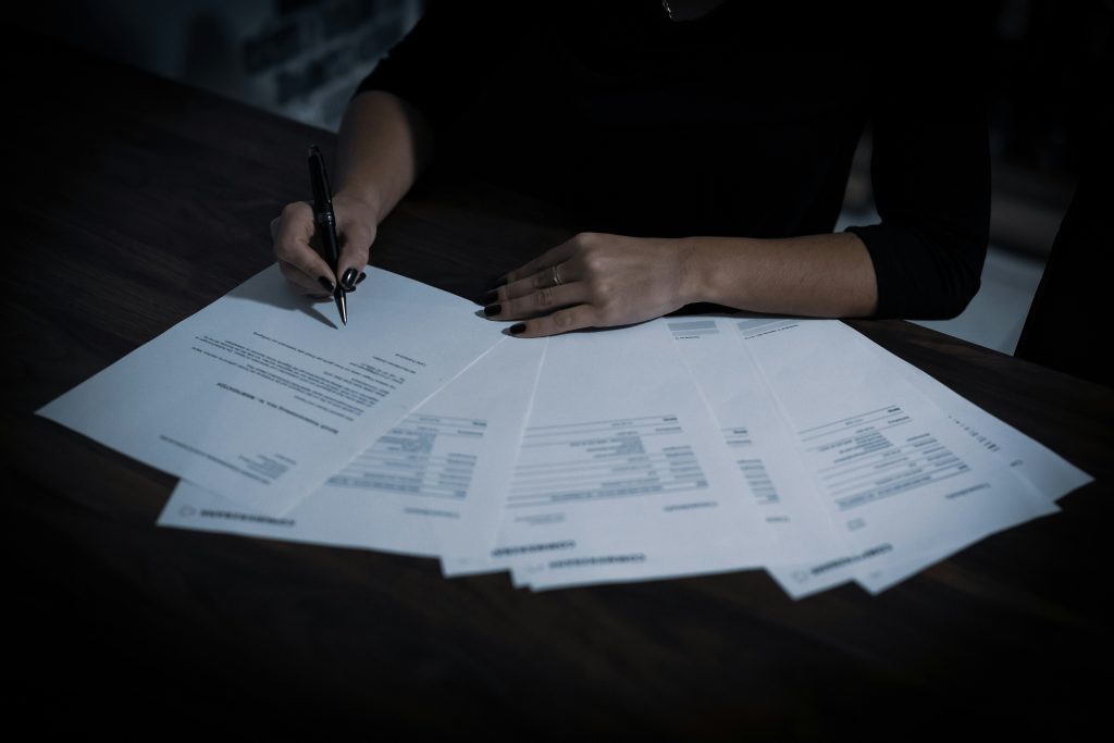 NDA in M&A: Protecting Confidentiality During a Sale 2 Person signing documents on table.
