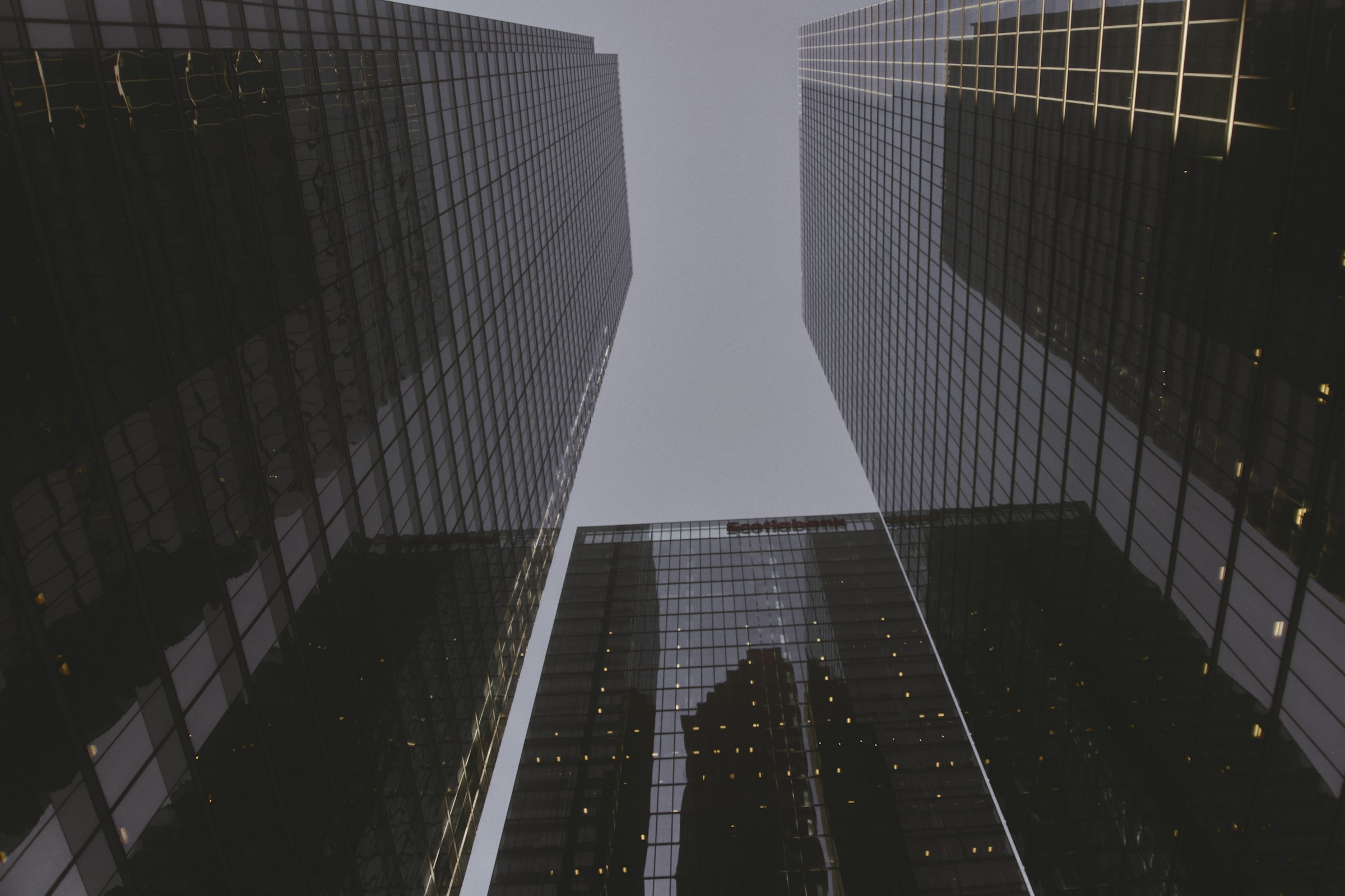 Looking up between dark glass office towers